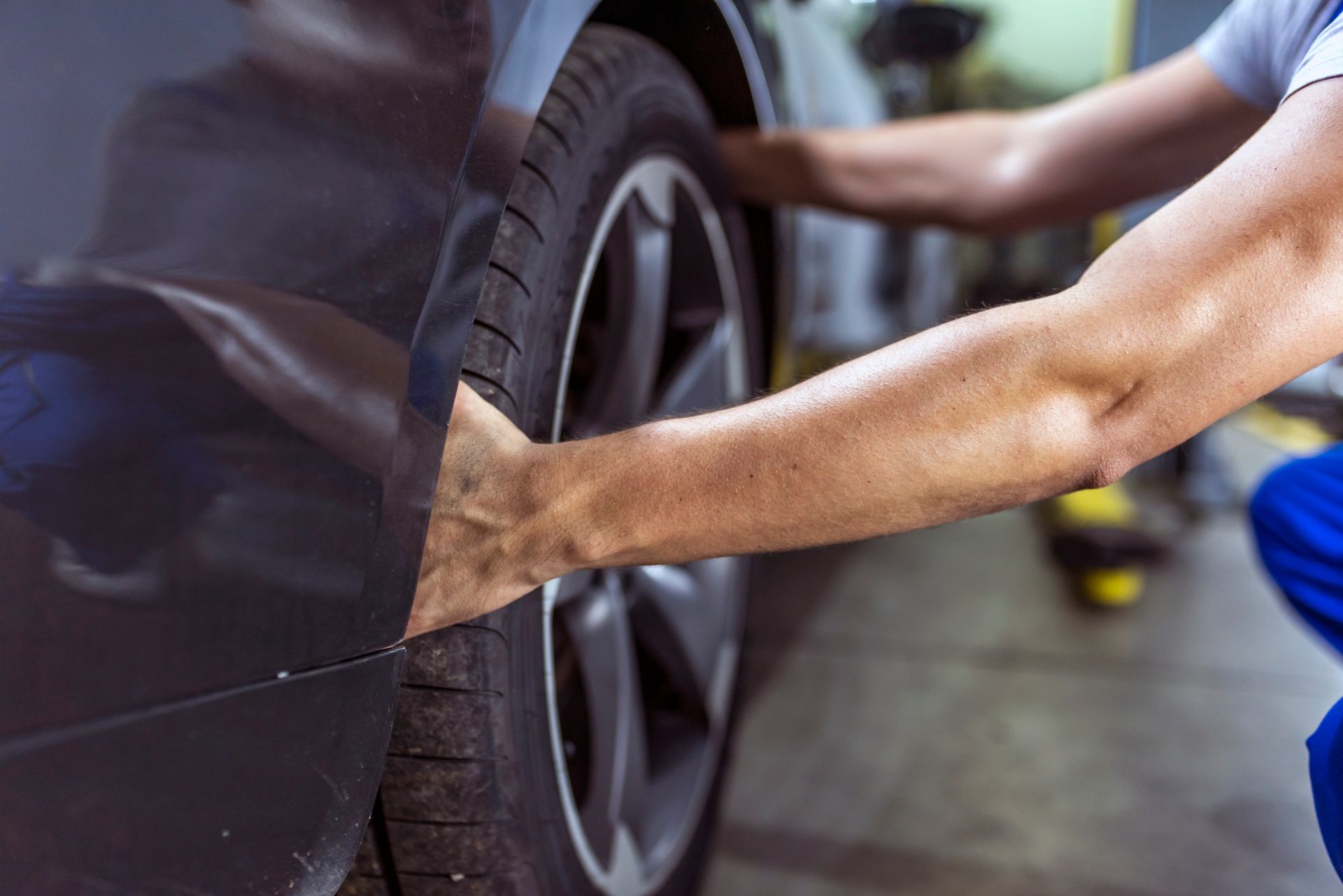 A man is changing a tire on a car in a garage.