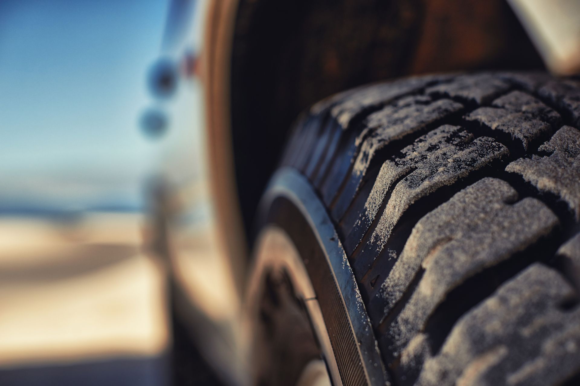 A close up of a car tire on a beach.