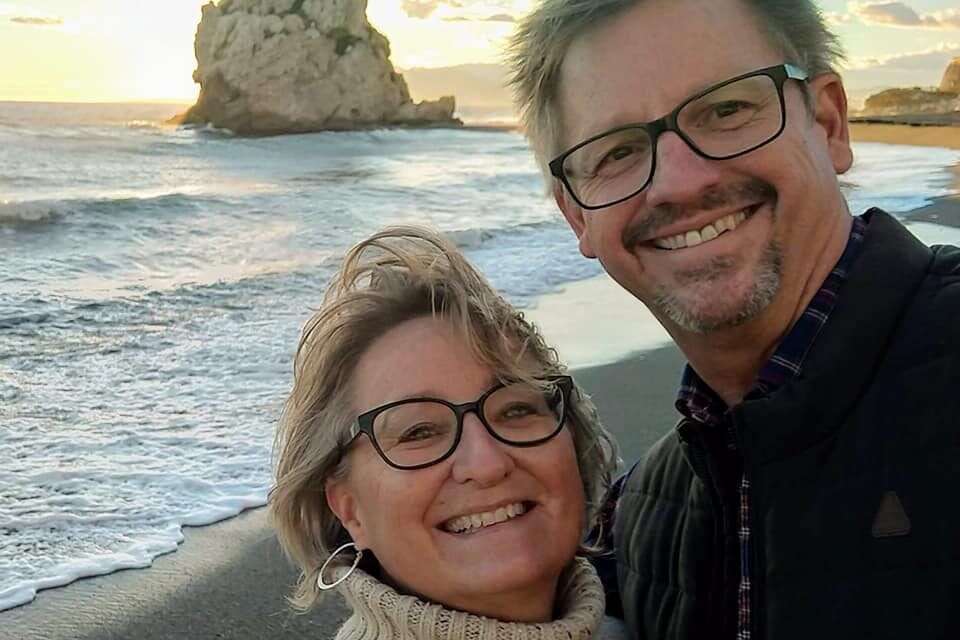 A man and a woman are posing for a picture on the beach.