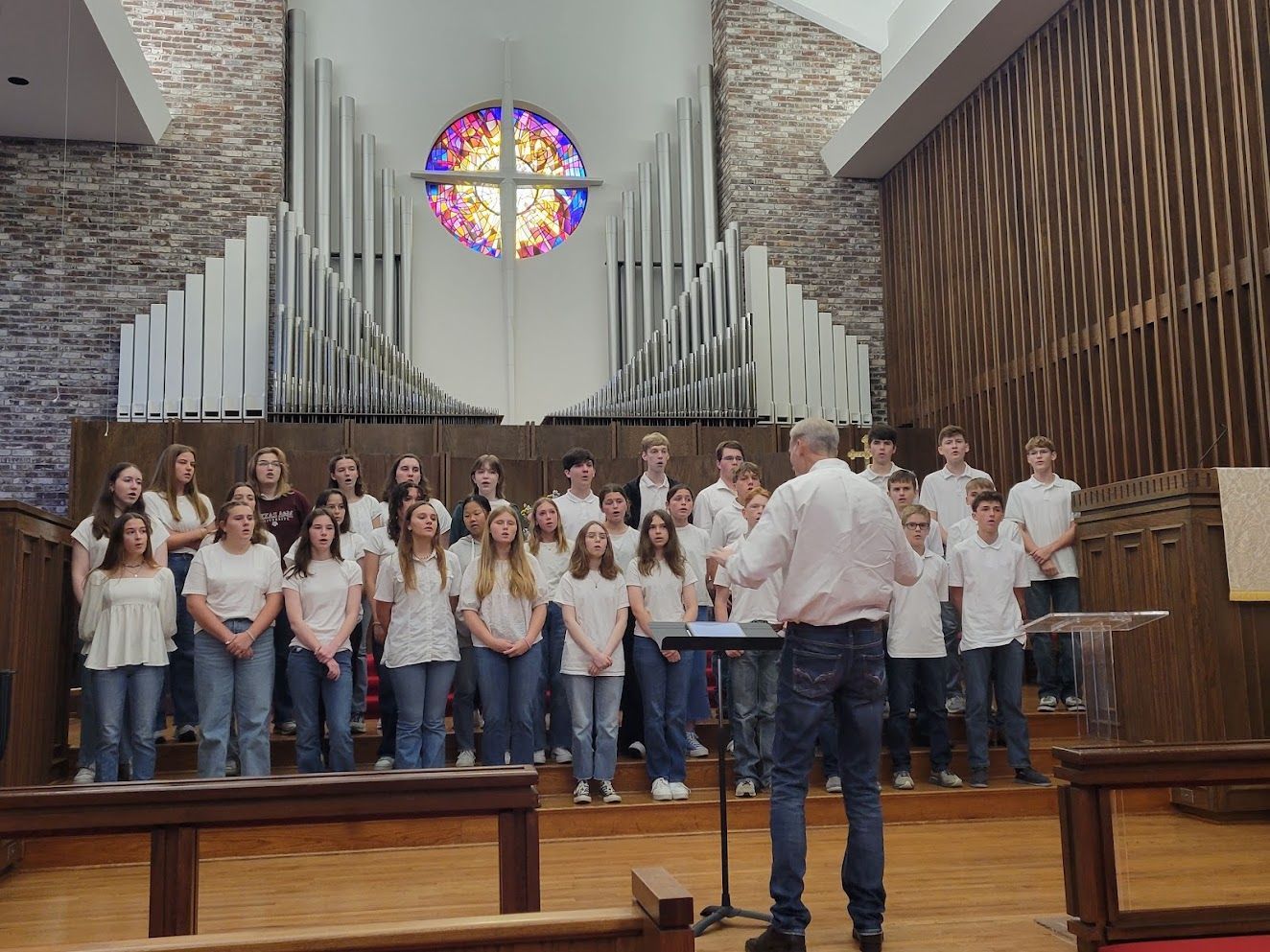 A man is standing in front of a choir in a church.