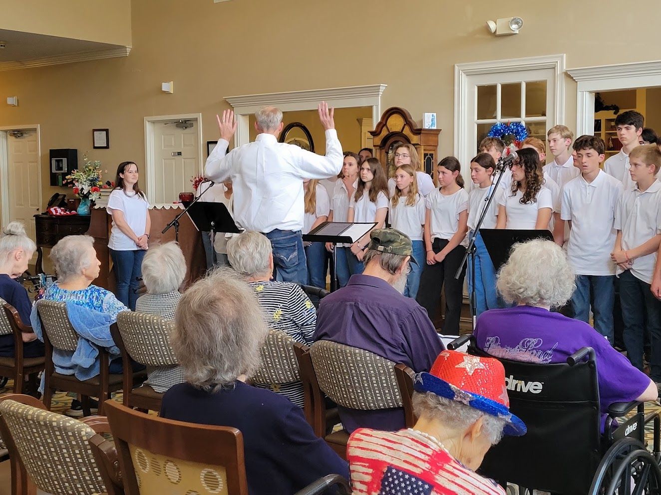 A group of people are sitting in chairs watching a choir sing.
