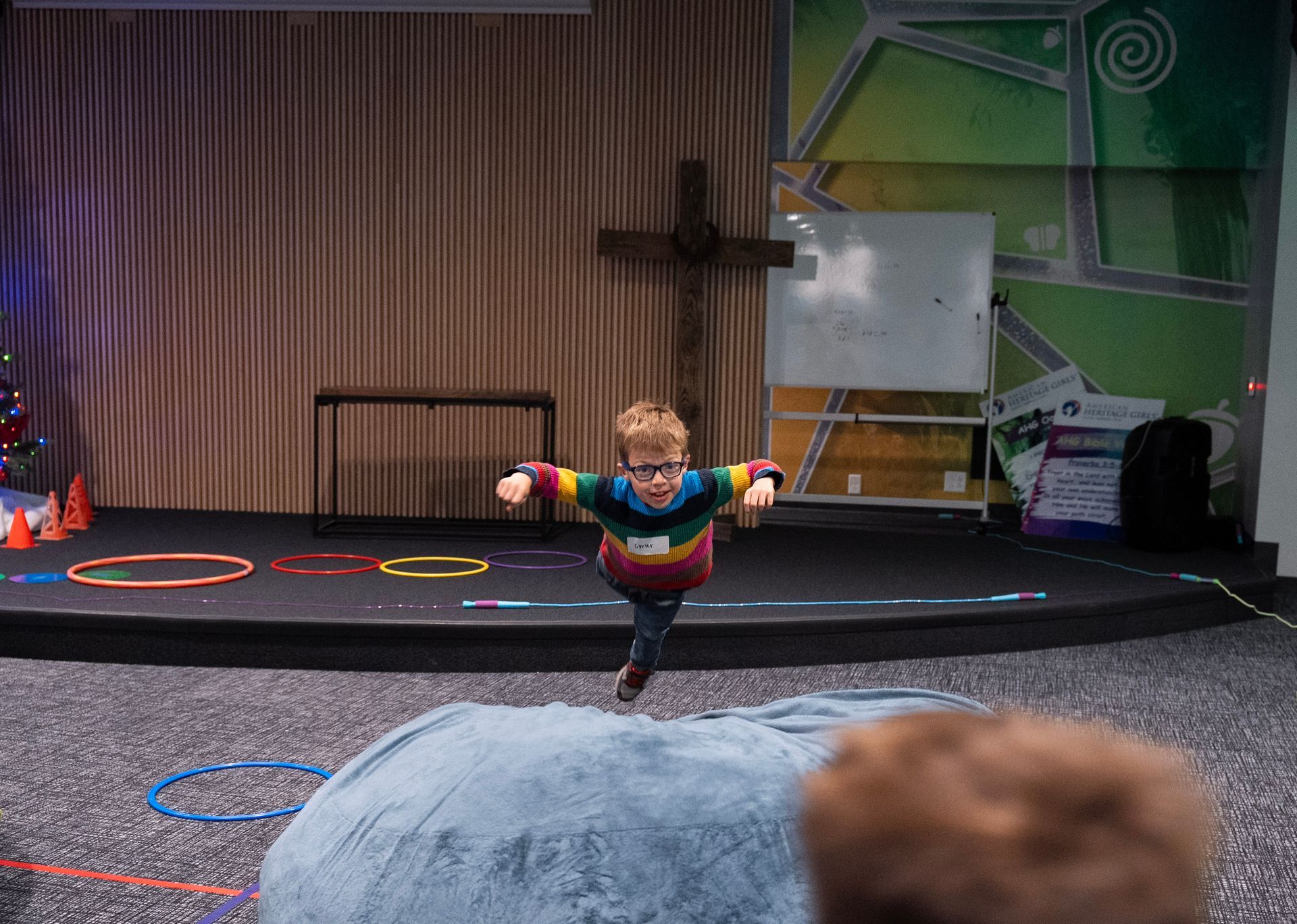 A young boy is jumping in the air in front of a stage.