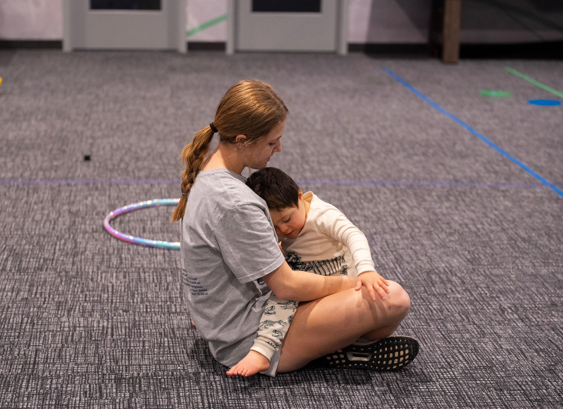A woman is sitting on the floor holding a child.