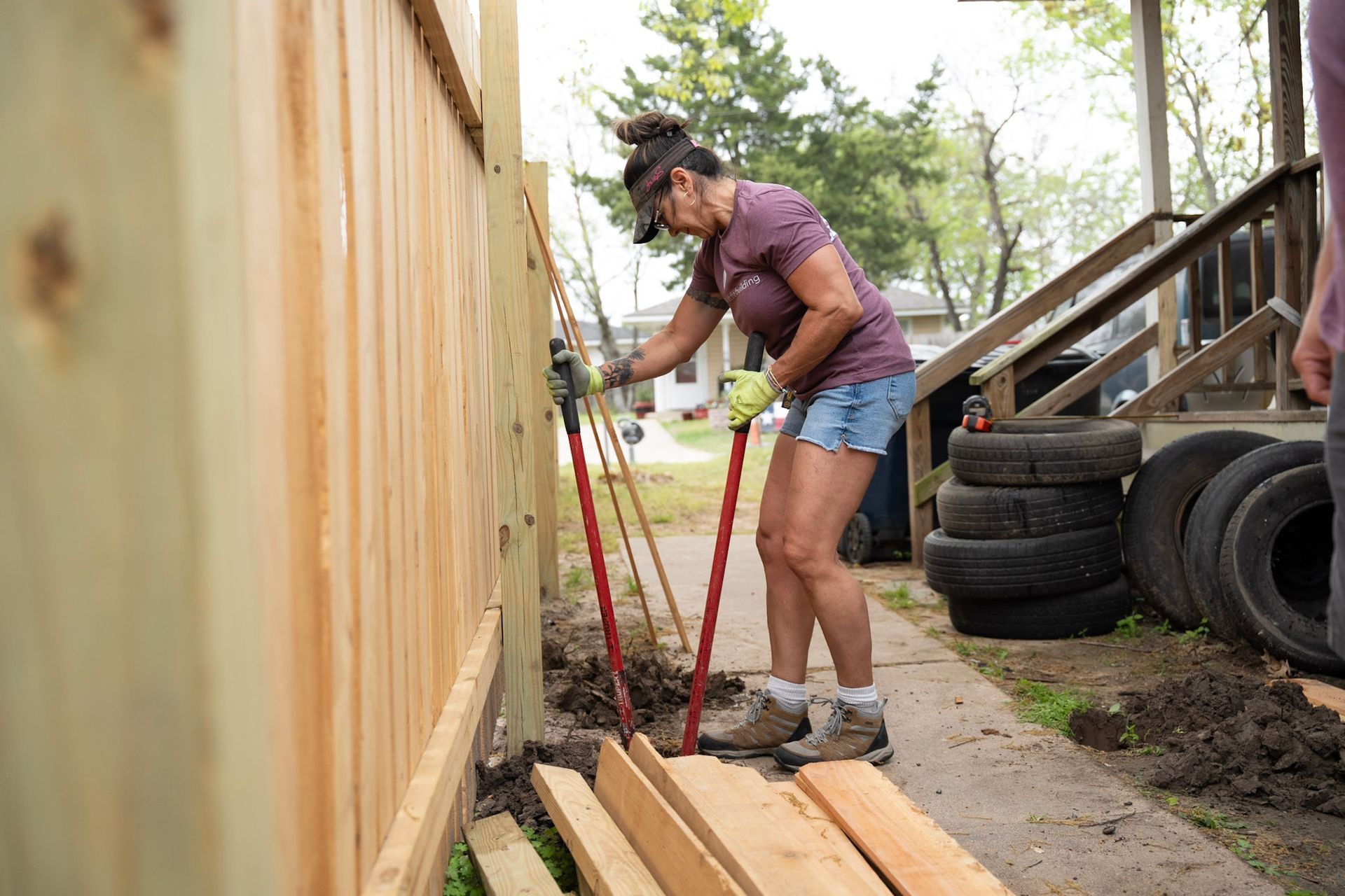 A group of people are standing in front of a white house constructing a wheelchair ramp.