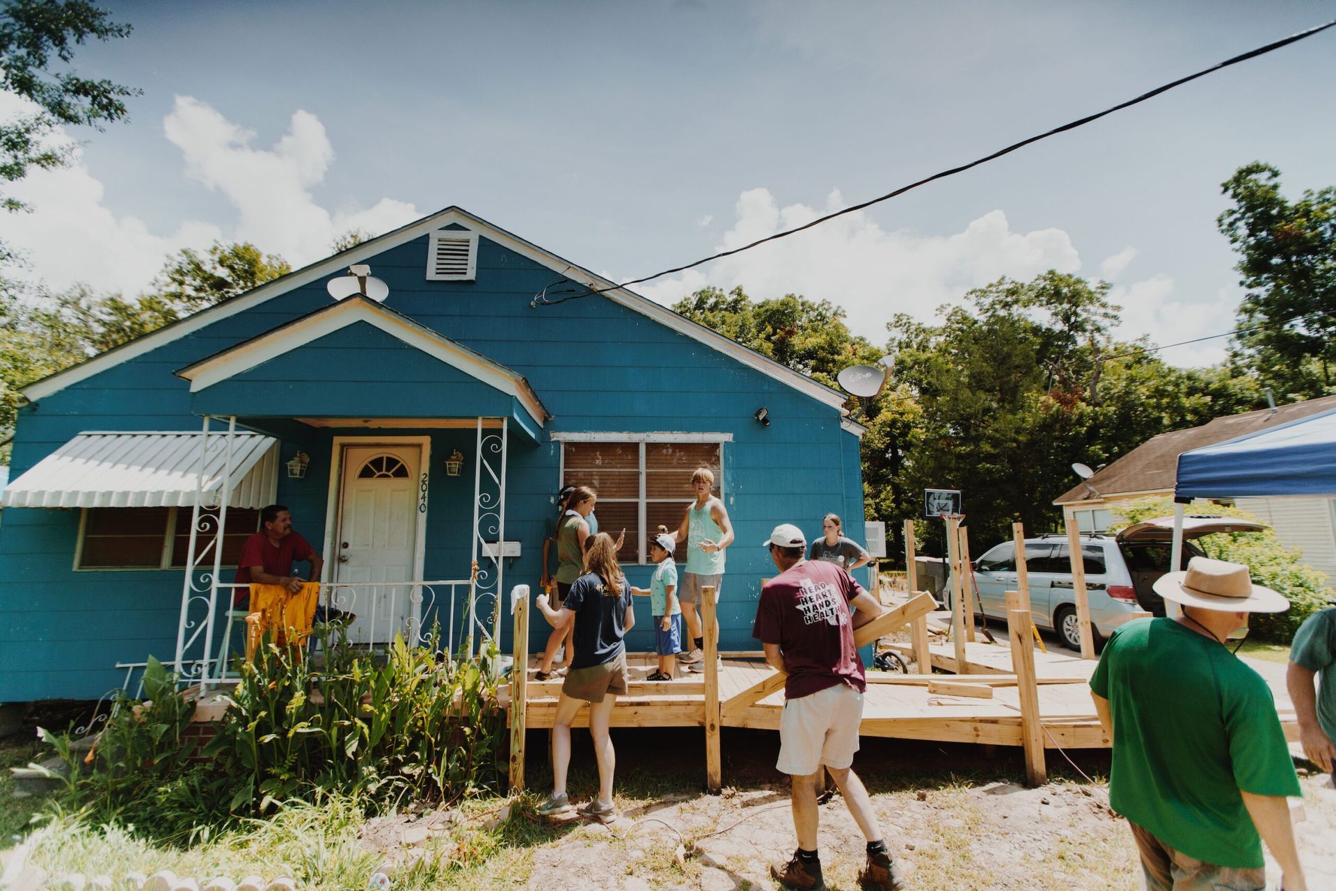 A group of people are working outside of a blue house