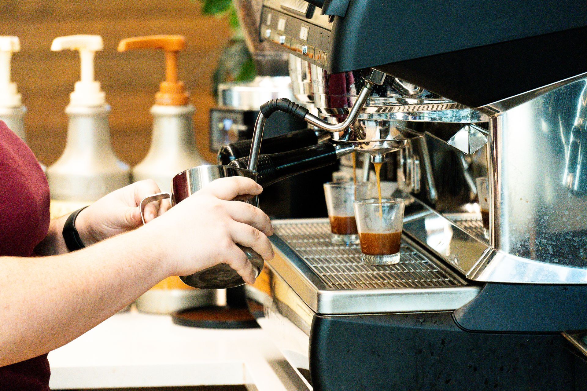 A barista pouring milk from a metal pitcher, making espresso in a cafe at Solid Grounds in College Station TX
