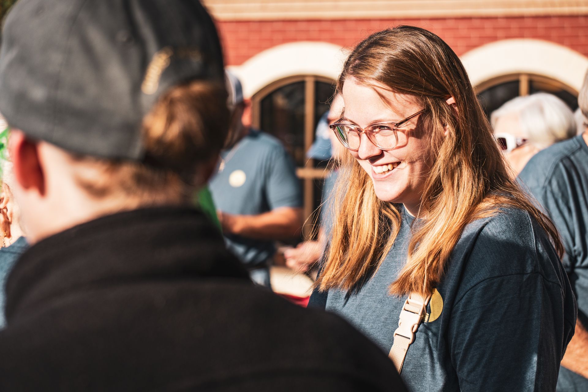 A woman wearing glasses is smiling while talking to a man.