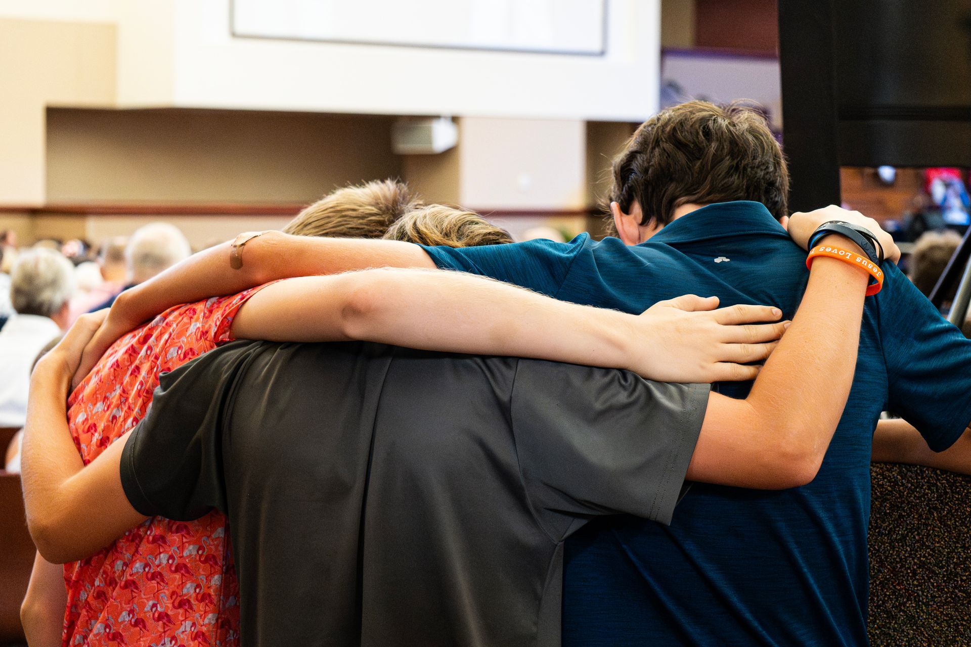 A group of people are hugging each other in a circle in prayer.