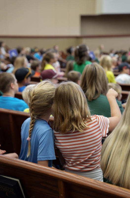 A group of young people are standing around a boy wearing a cougar jersey.