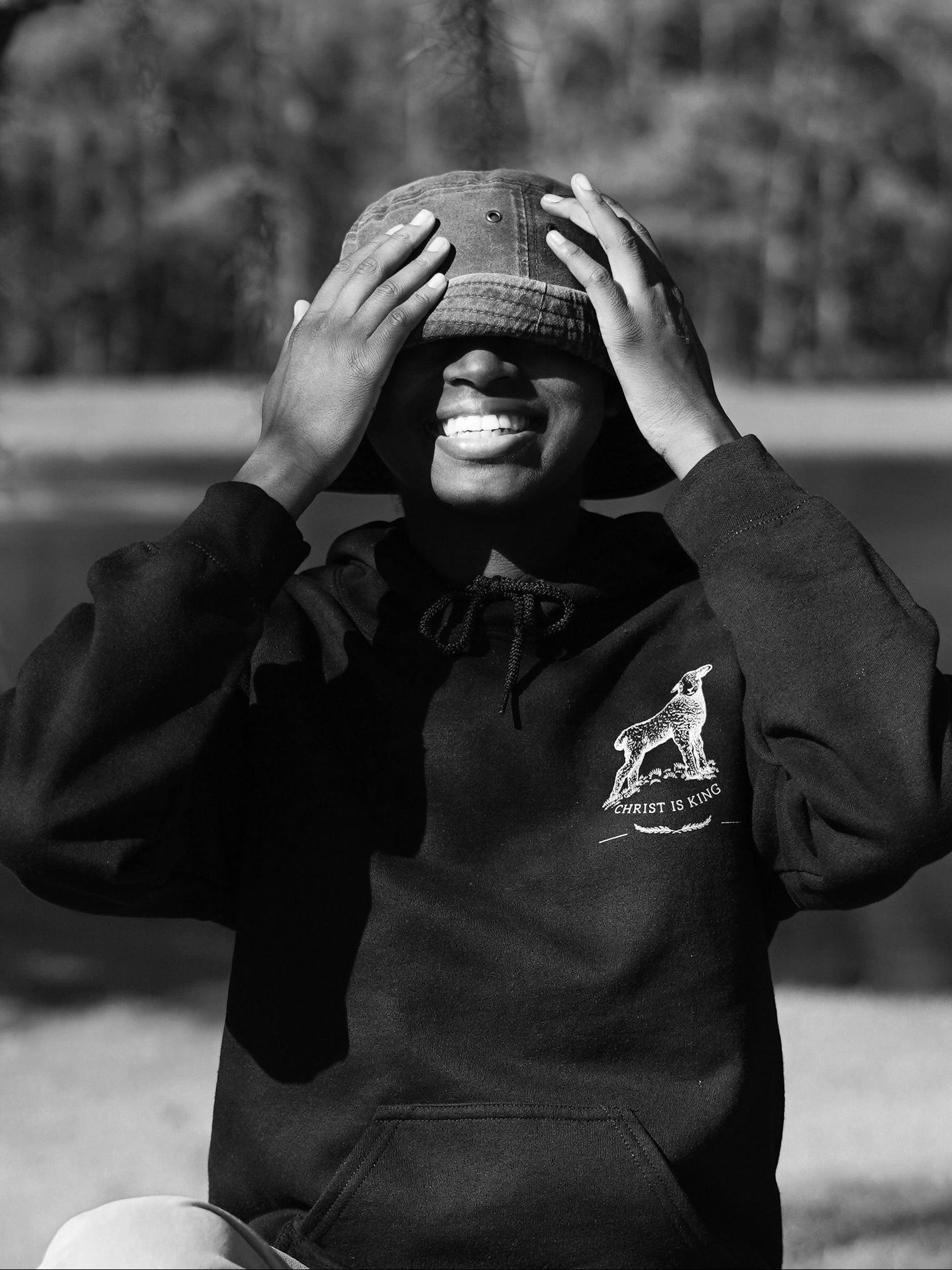 A black and white photo of a person covering their face with a hat