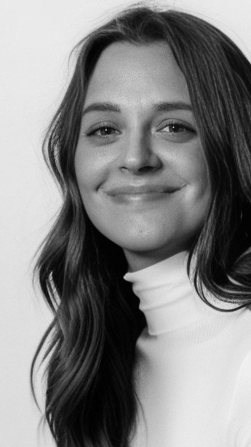 A black and white photo of a woman wearing a white turtleneck and smiling.