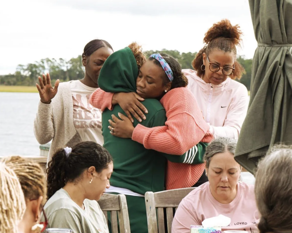 A woman in a pink nike shirt is hugging another woman