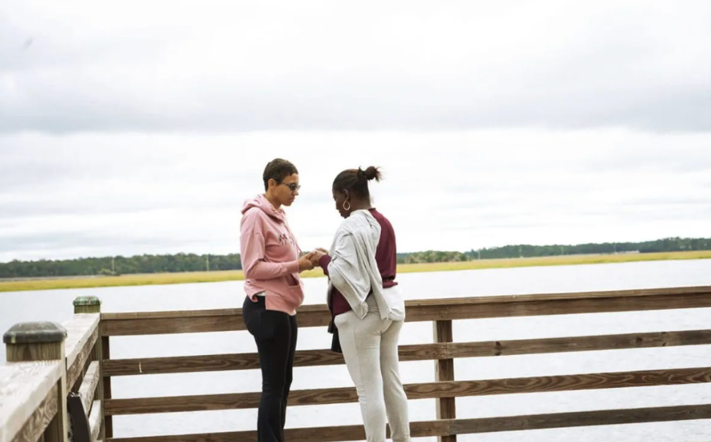 A man is proposing to a woman on a dock.