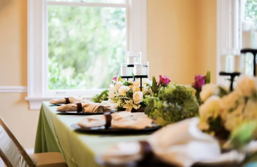 A long table with plates , napkins , candles and flowers on it.