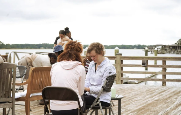 A group of people are sitting on a dock near a body of water.