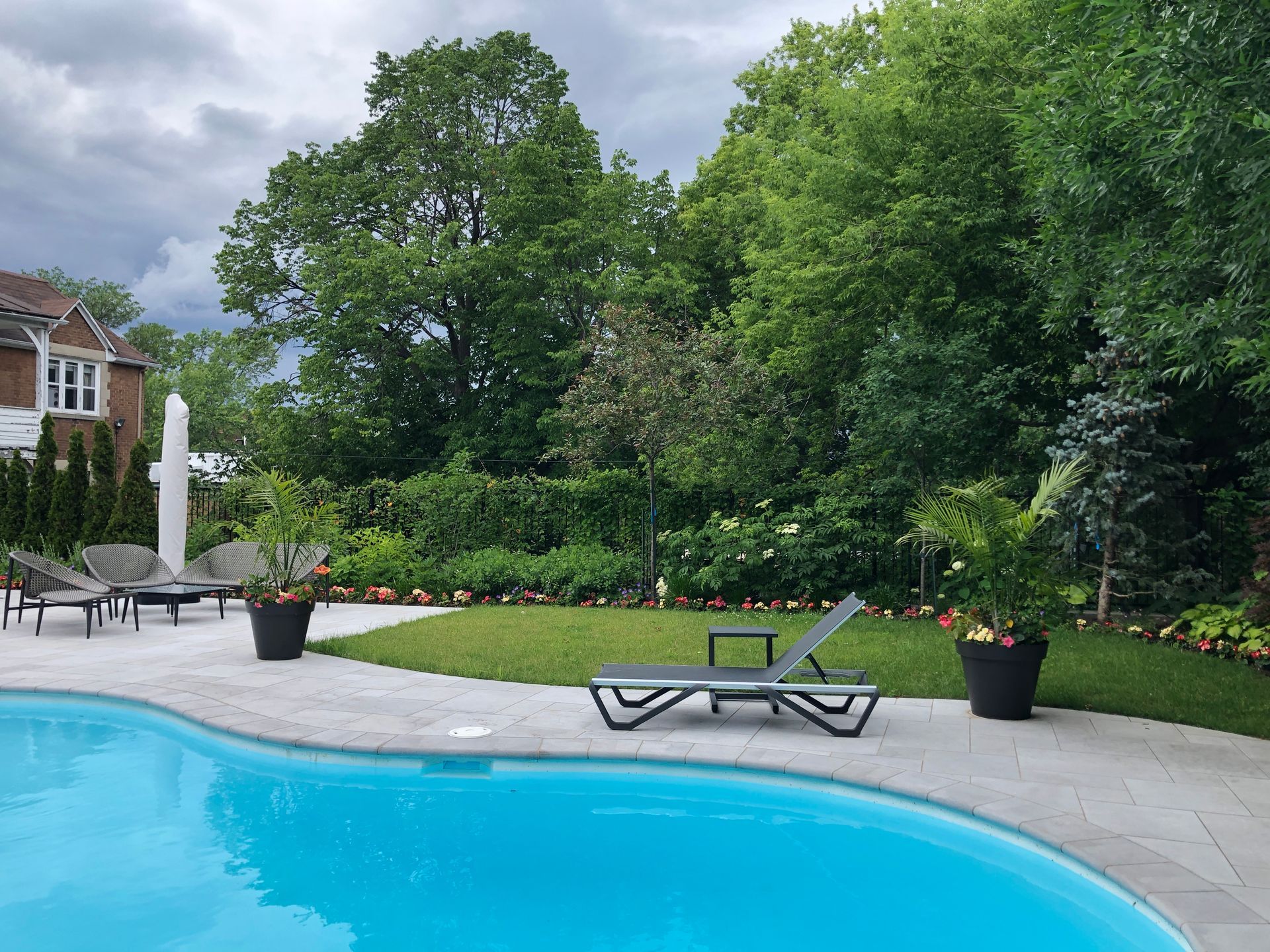 Une grande piscine entourée d'arbres et de chaises dans une cour arrière.