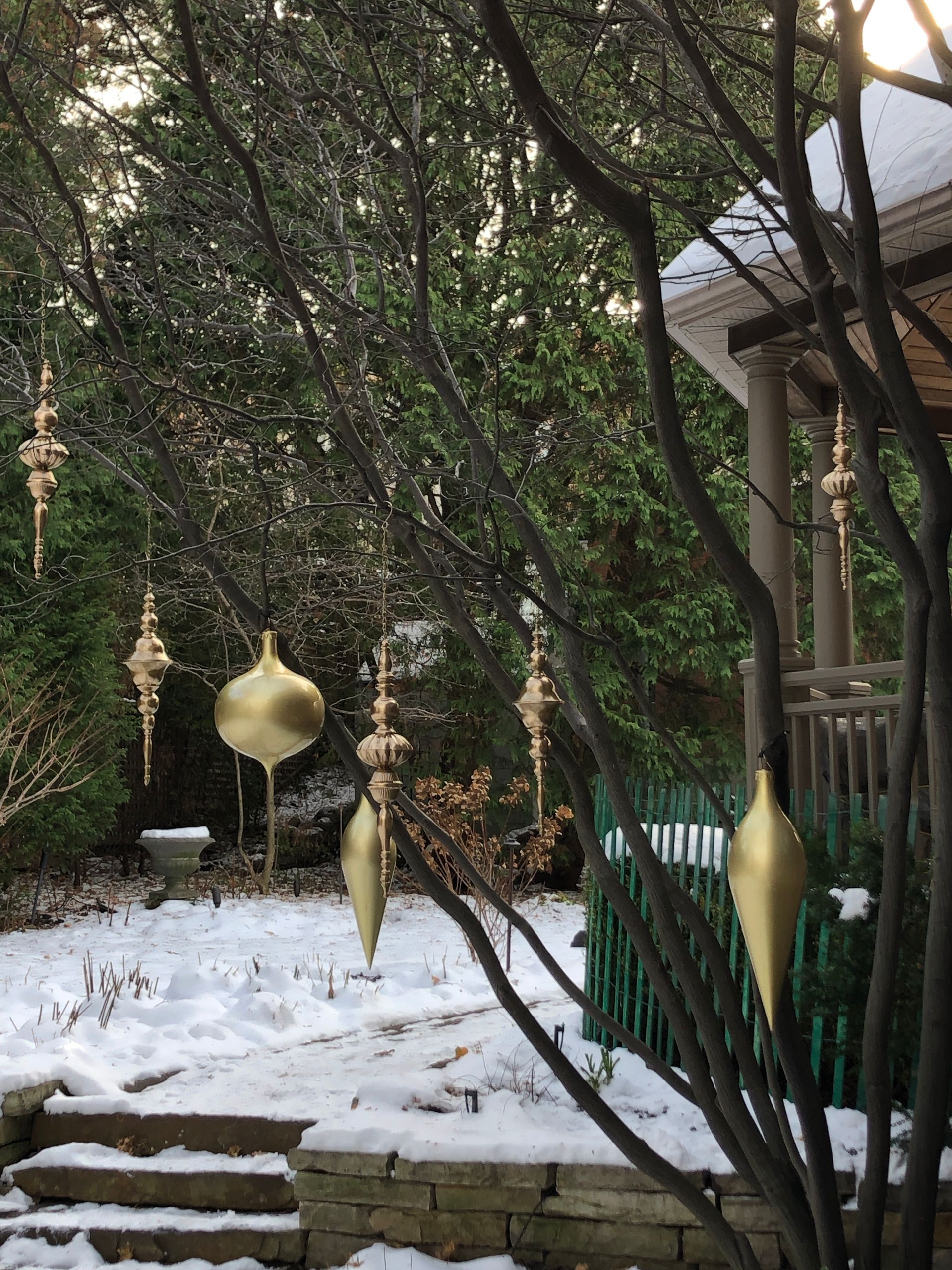 Christmas ornaments hanging from a tree in a snowy yard