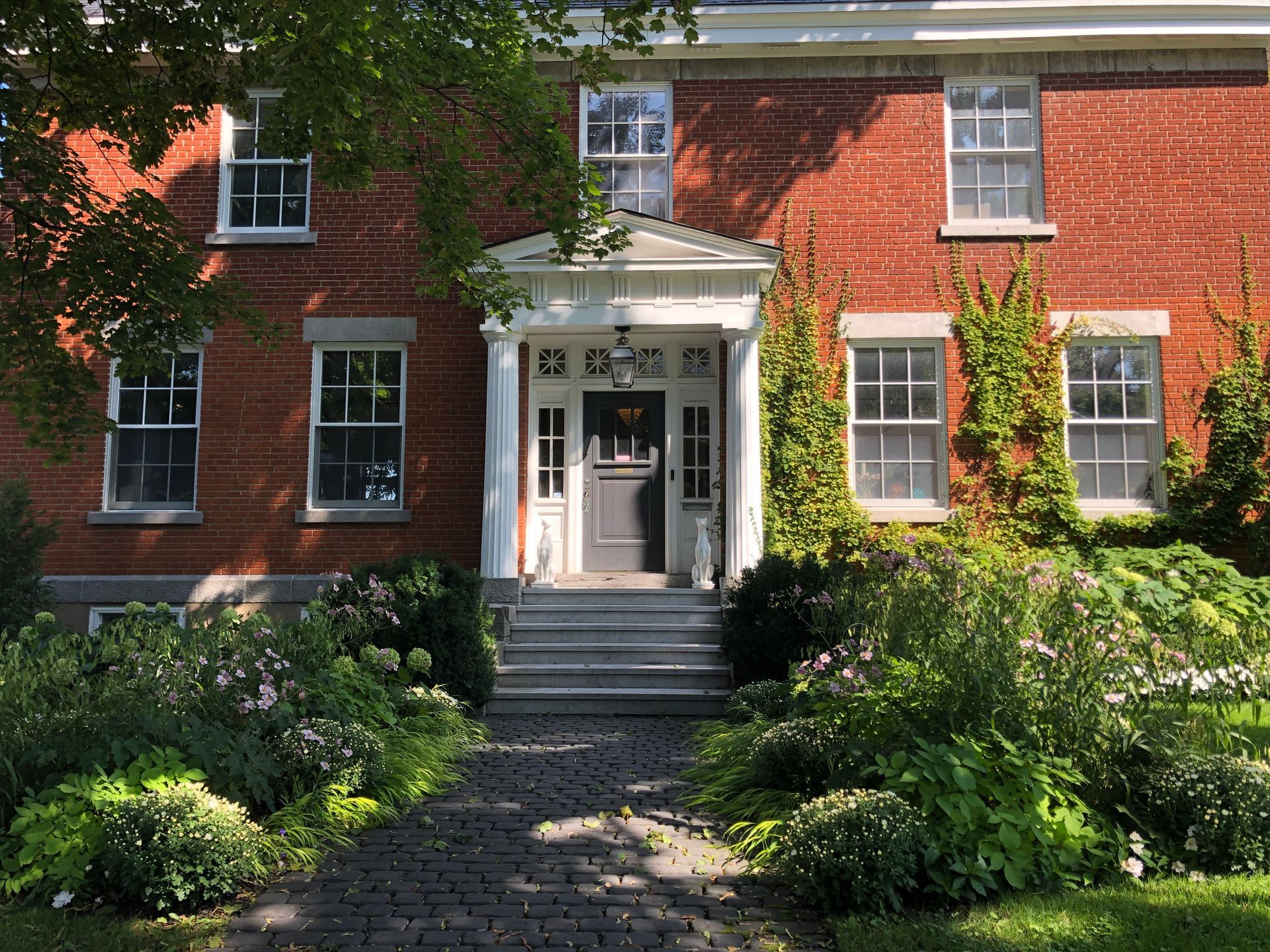 Une maison en brique avec un porche blanc et des escaliers