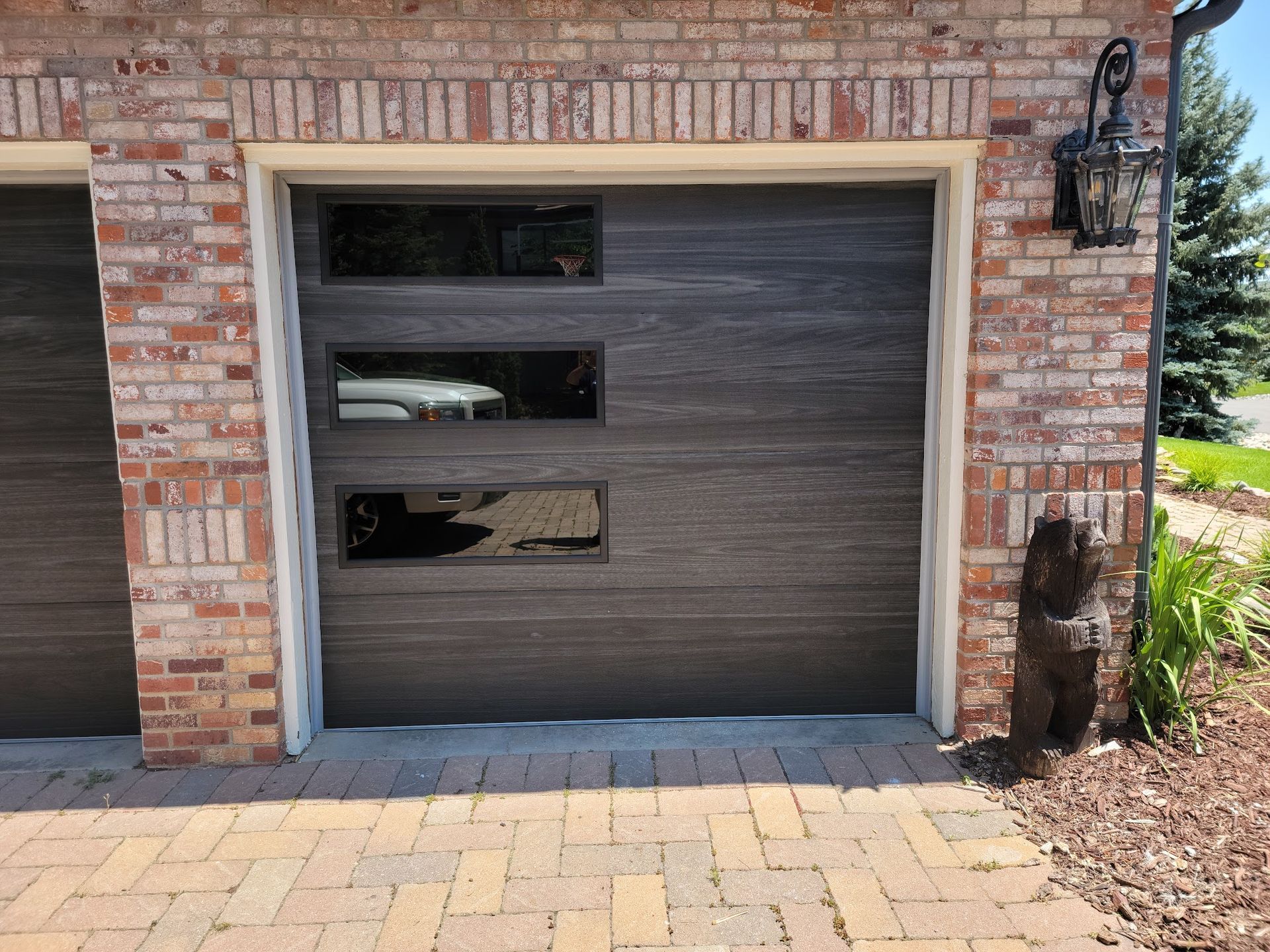Brown garage door with windows, set in a brick wall.