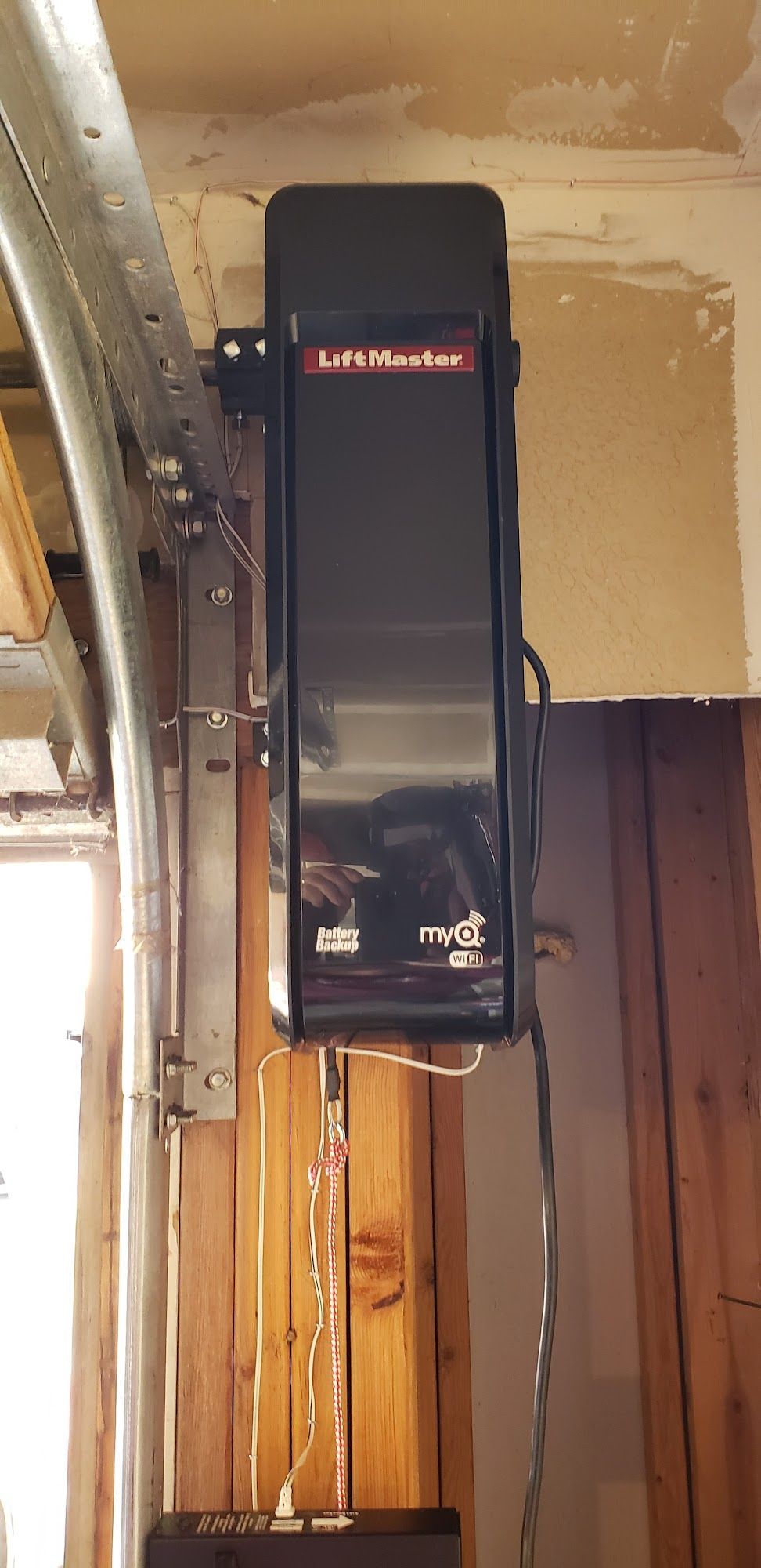 A LiftMaster garage door opener is installed on a wooden wall.