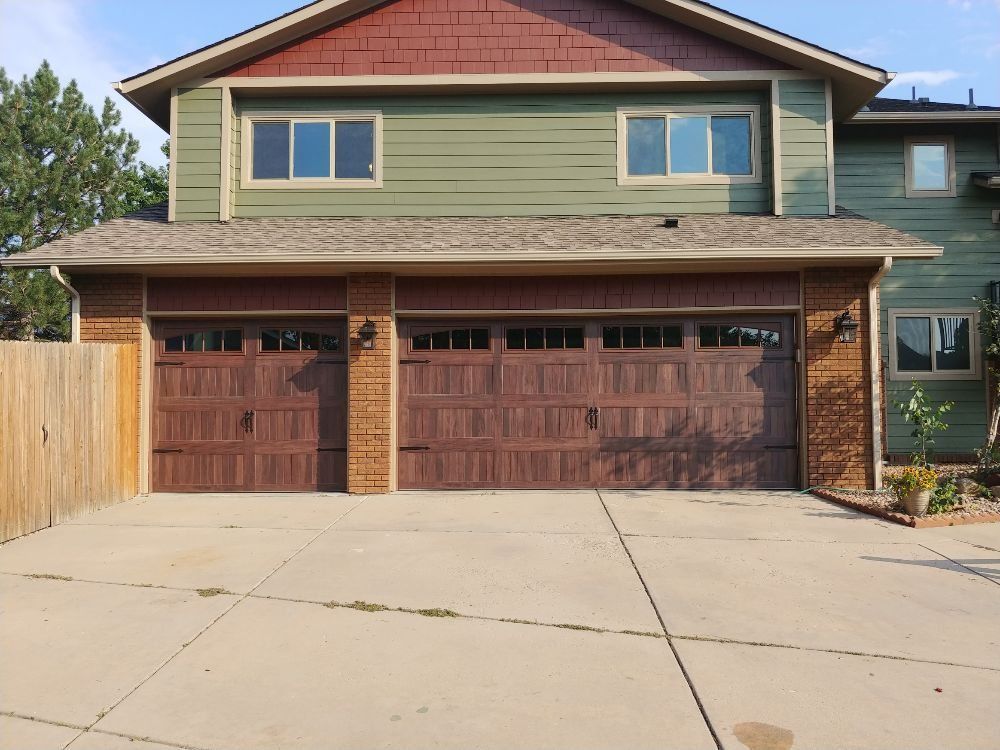Two-story house with a garage. Brown garage doors and siding, green exterior walls. Concrete driveway.