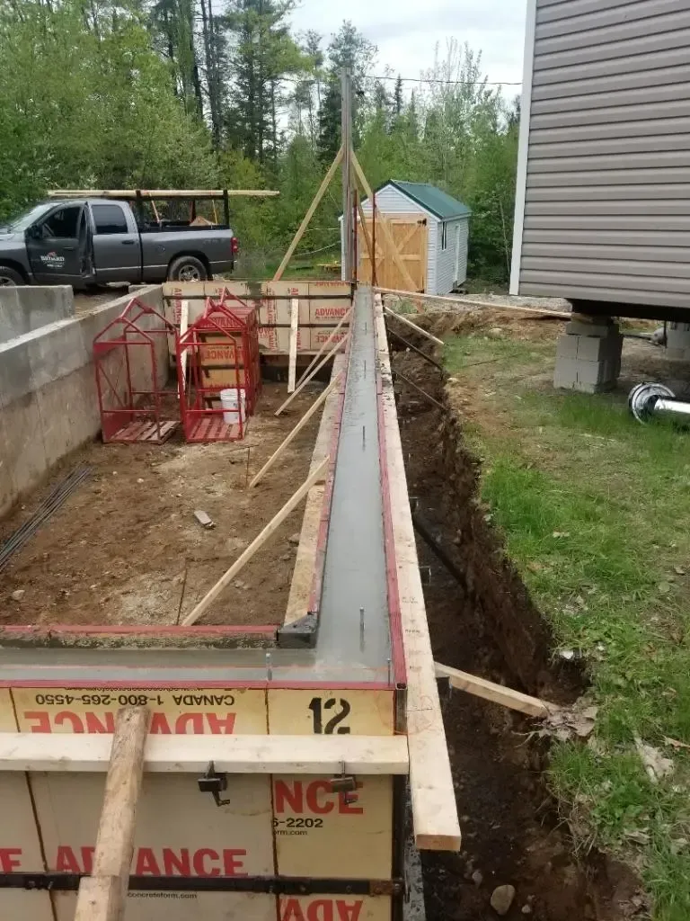 A concrete wall is being built in front of a house.