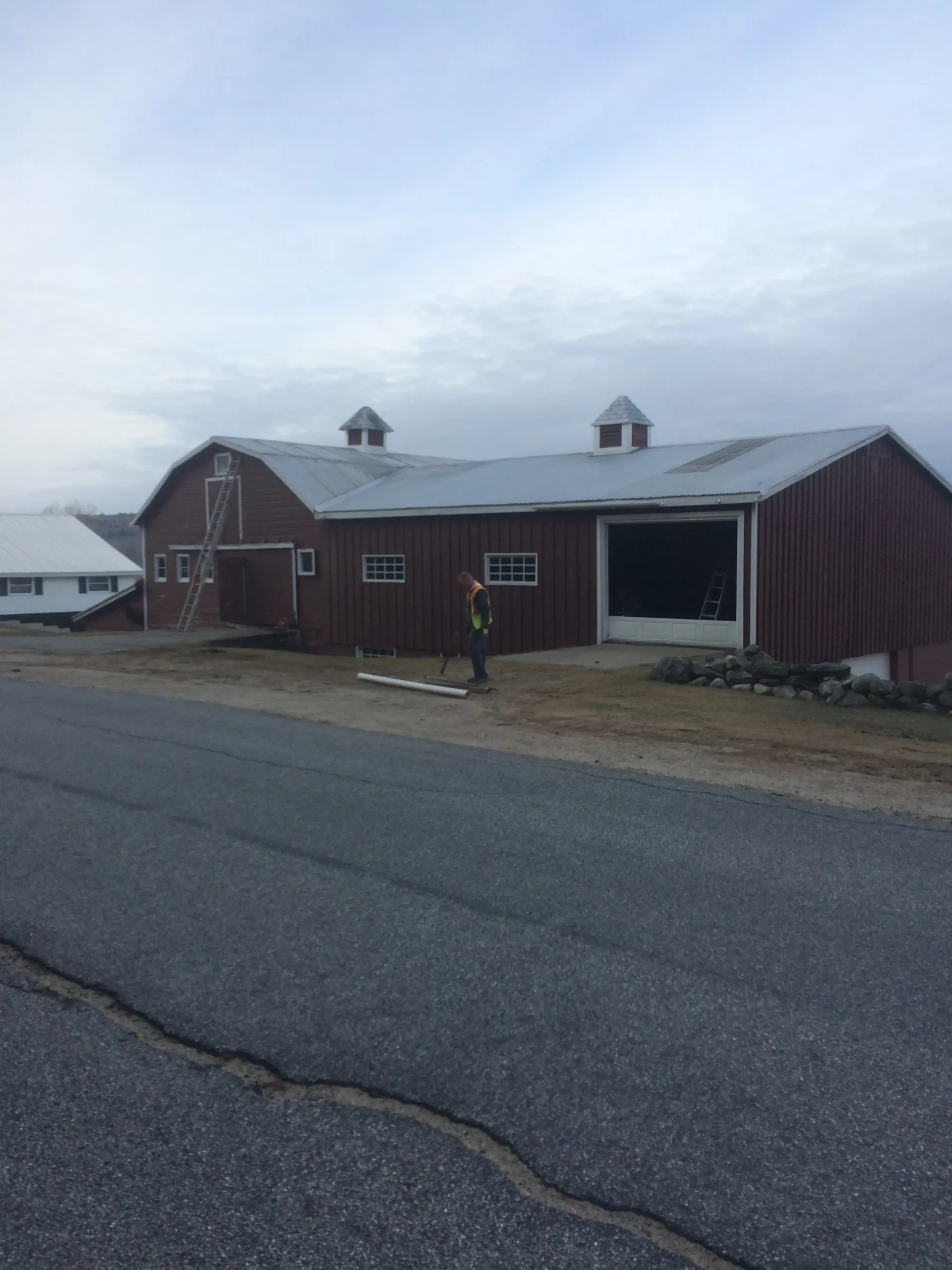 A man is standing in front of a large barn.