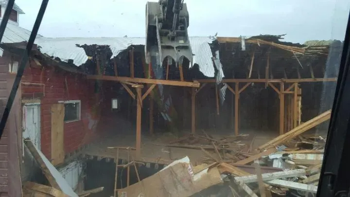 A large building is being demolished by a crane.