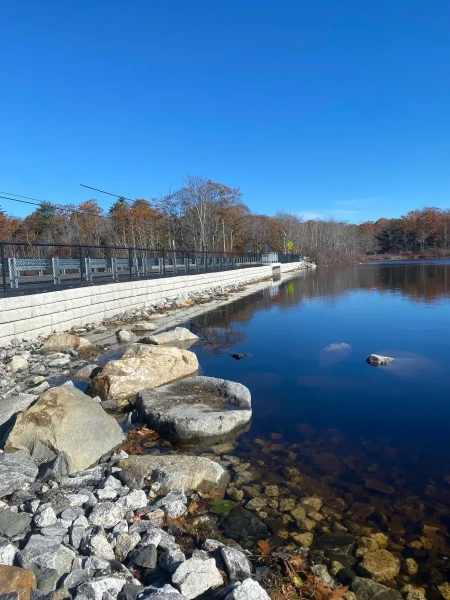A large body of water surrounded by rocks and trees on a sunny day.