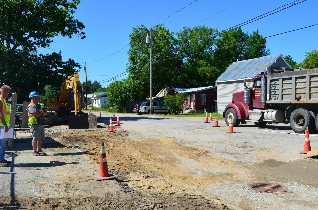 A red dump truck is driving down a dirt road.
