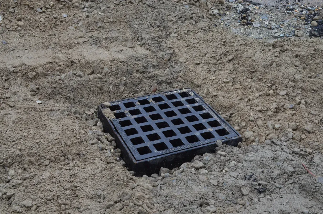A black manhole cover is sitting in the dirt