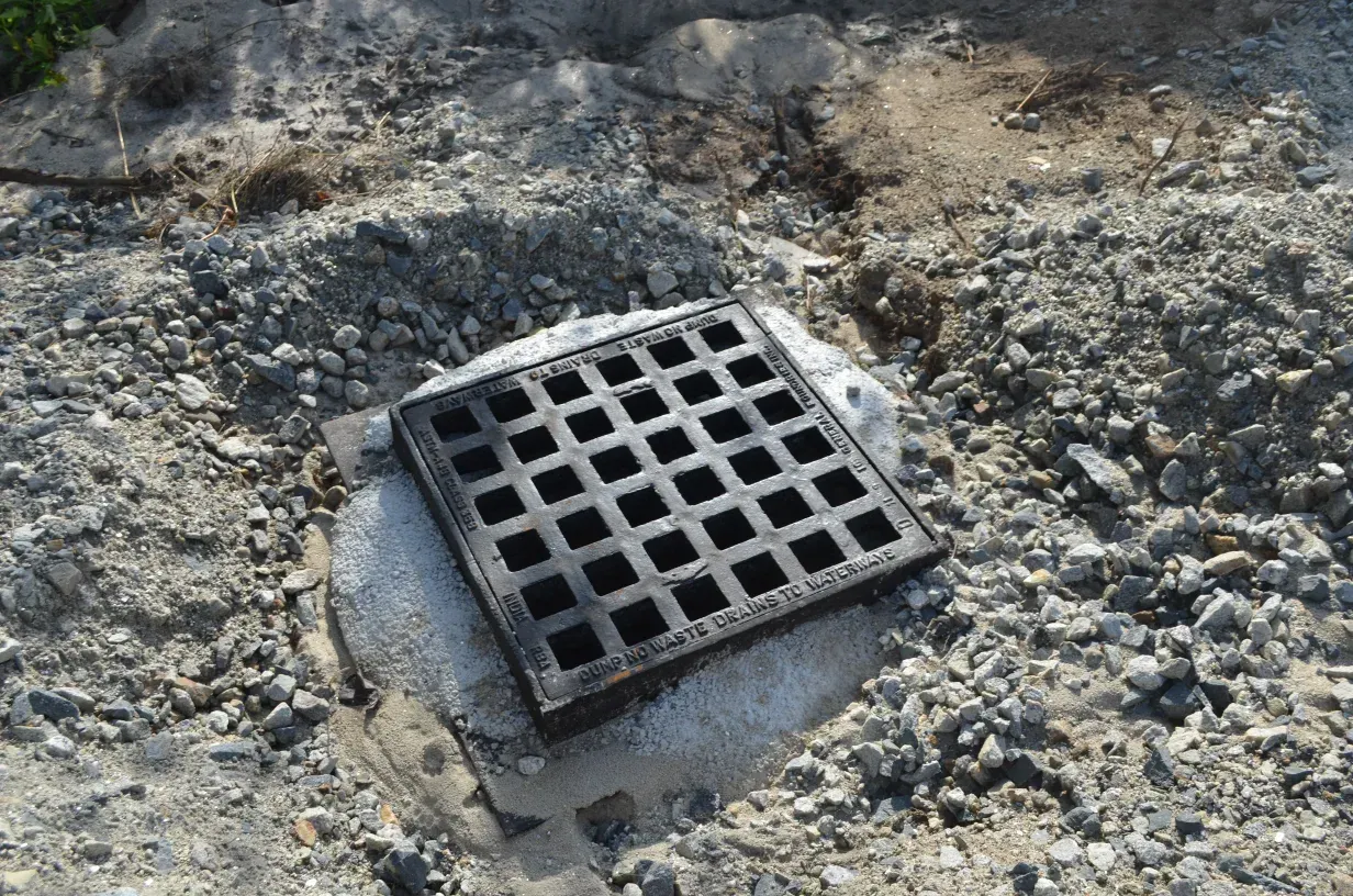 A manhole cover is sitting on top of a rock in the dirt.