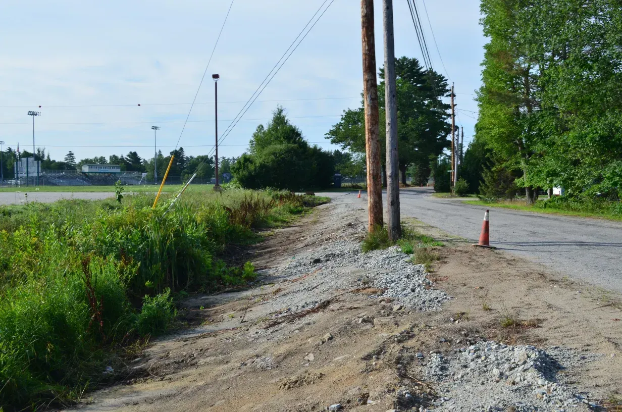 A dirt road with a red cone on the side of it.
