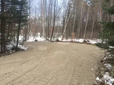 A dirt road in the middle of a snowy forest.