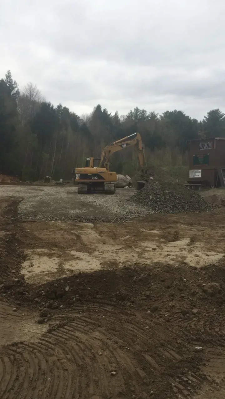 A large yellow excavator is sitting in the middle of a dirt field.