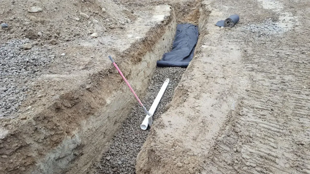 A pipe is laying in the dirt next to a red line.