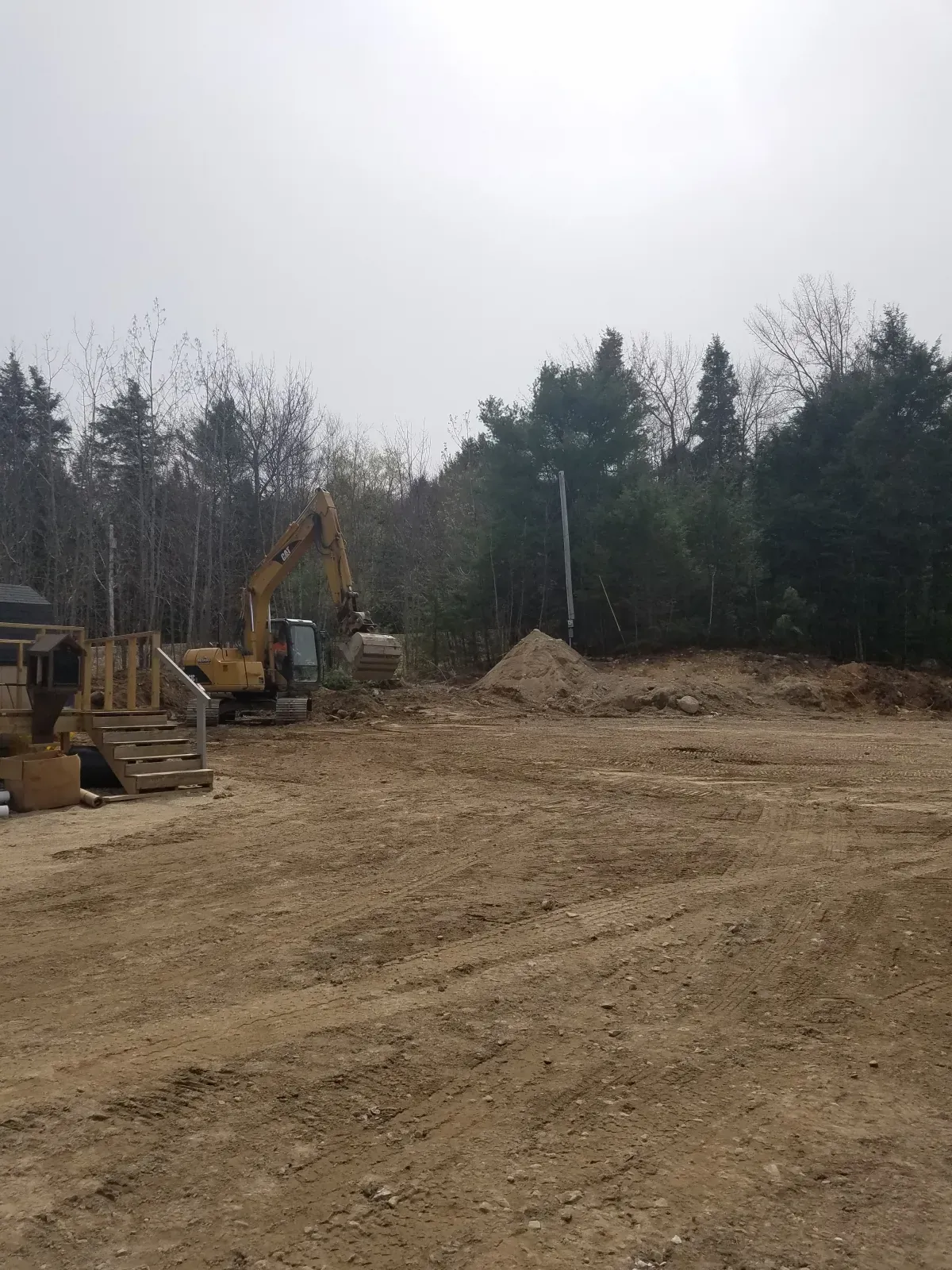 A construction site with a lot of dirt and trees in the background.