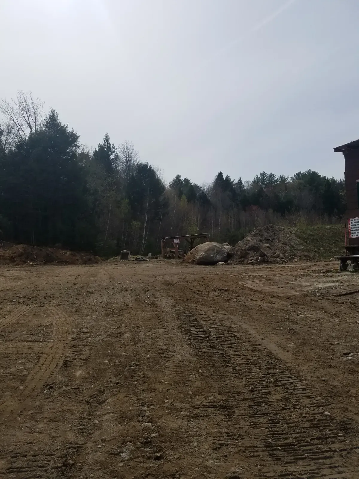 A dirt field with trees in the background and a building in the background.