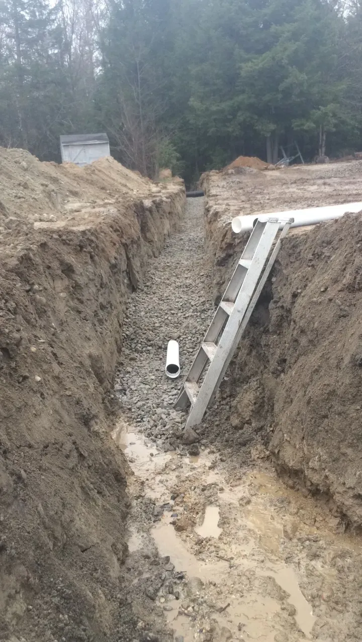 A ladder is sitting in the middle of a muddy trench.