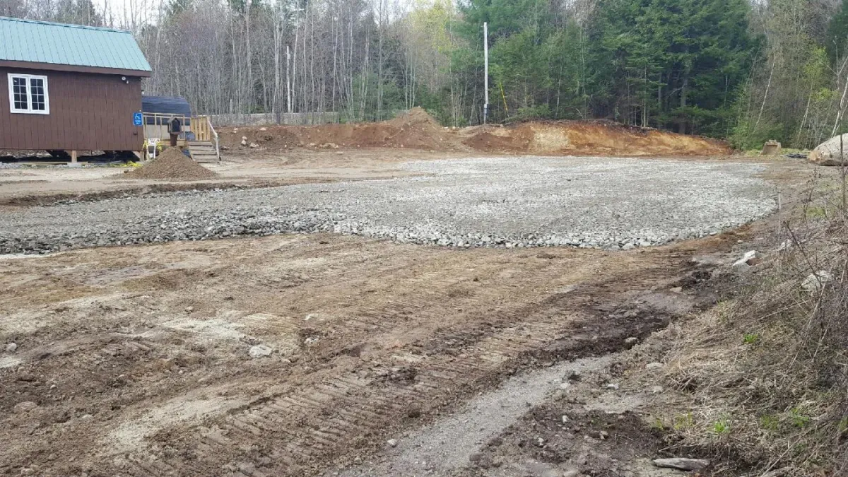 A dirt road leading to a house in the woods.