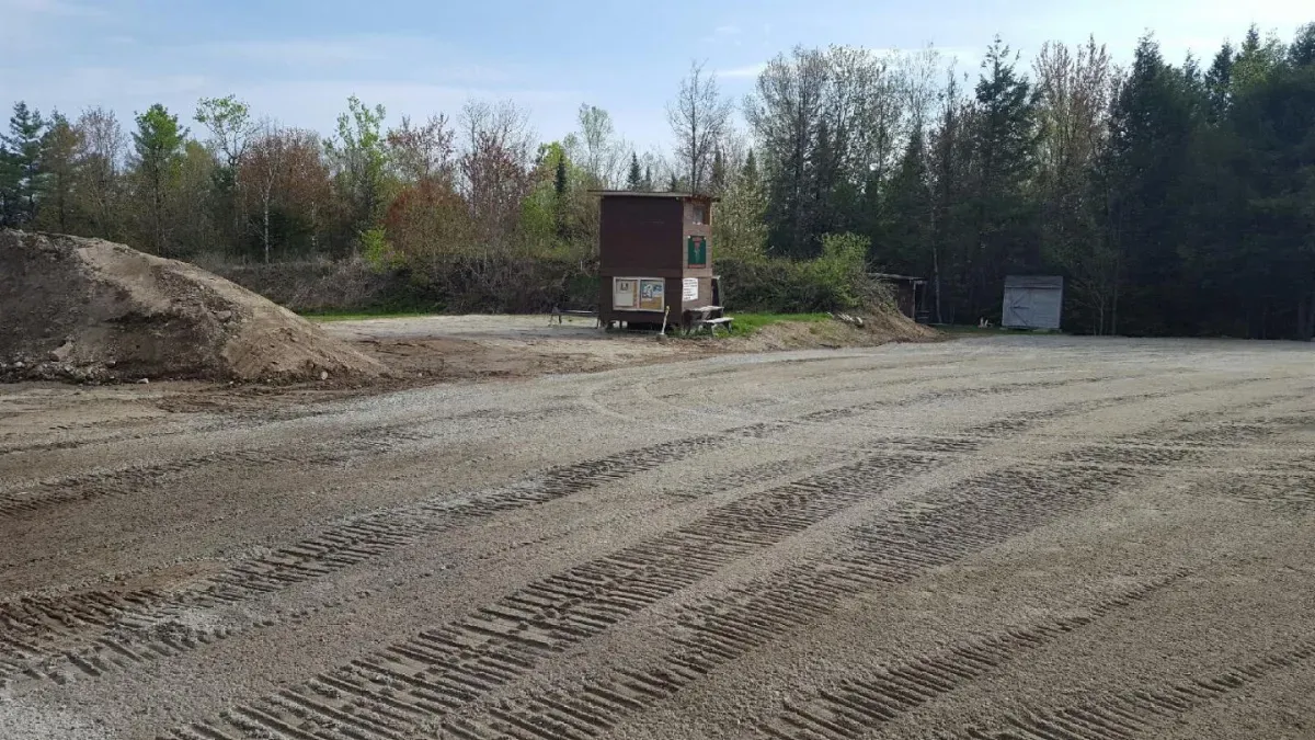 A large dirt field with a shed in the middle of it.