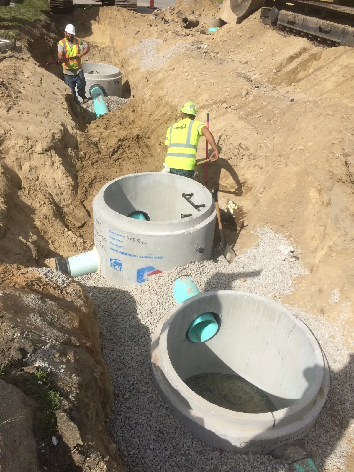 A group of construction workers are working on a drainage system in the dirt.