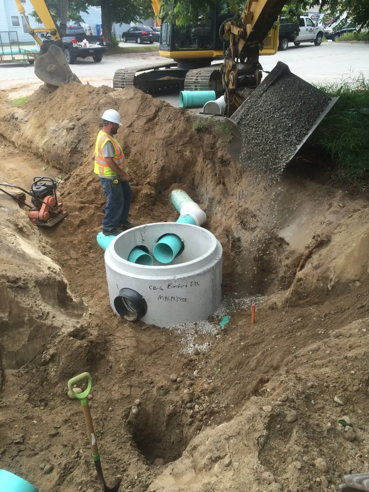 A man is standing in a hole with pipes in it.