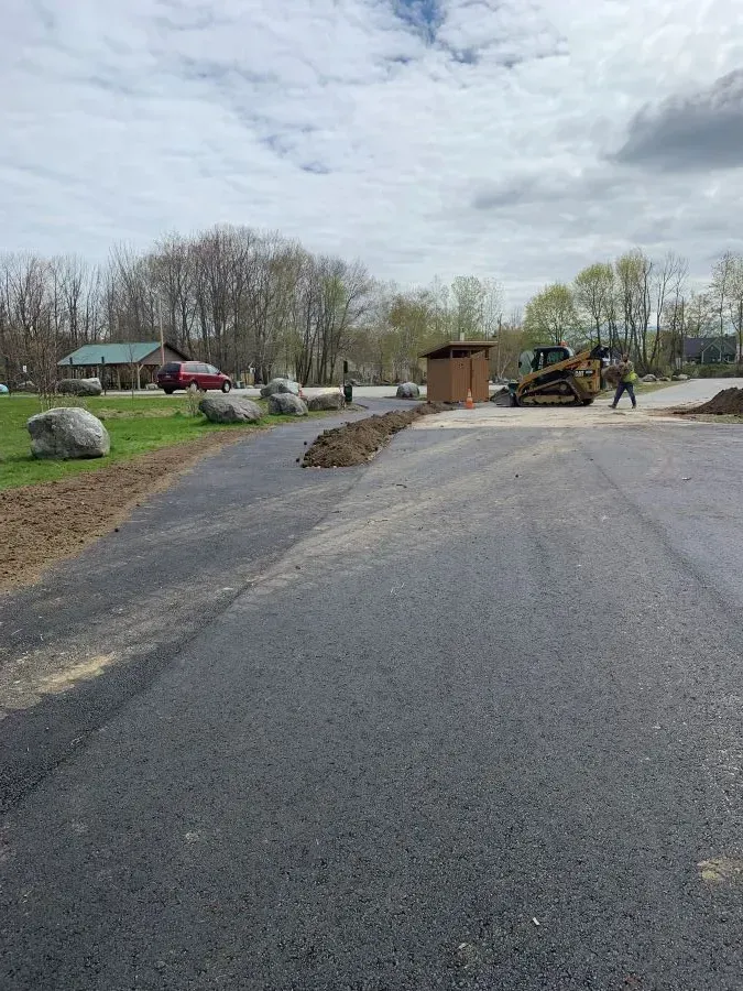 A man is walking down a road next to a bulldozer.