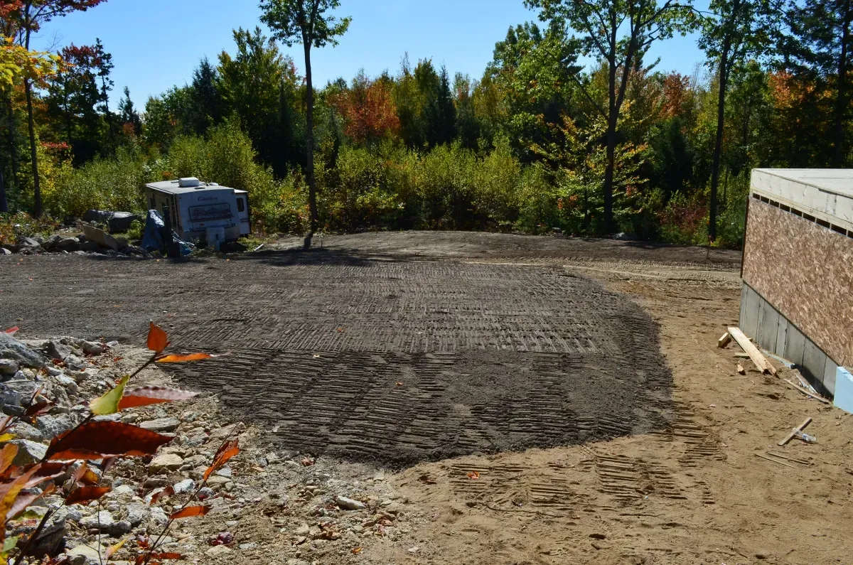 A brick building is being built in the middle of a dirt field.