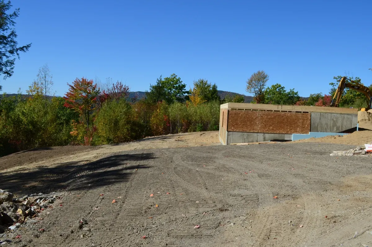 A dirt road with a brick wall in the background