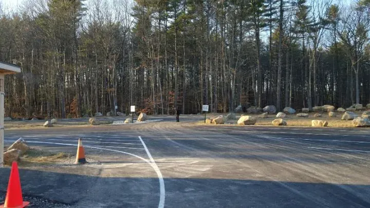 A parking lot with cones and trees in the background.
