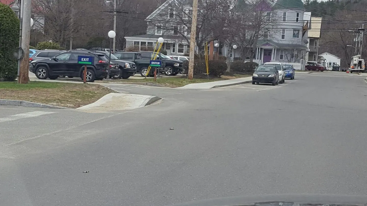 A row of cars are parked on the side of a street.