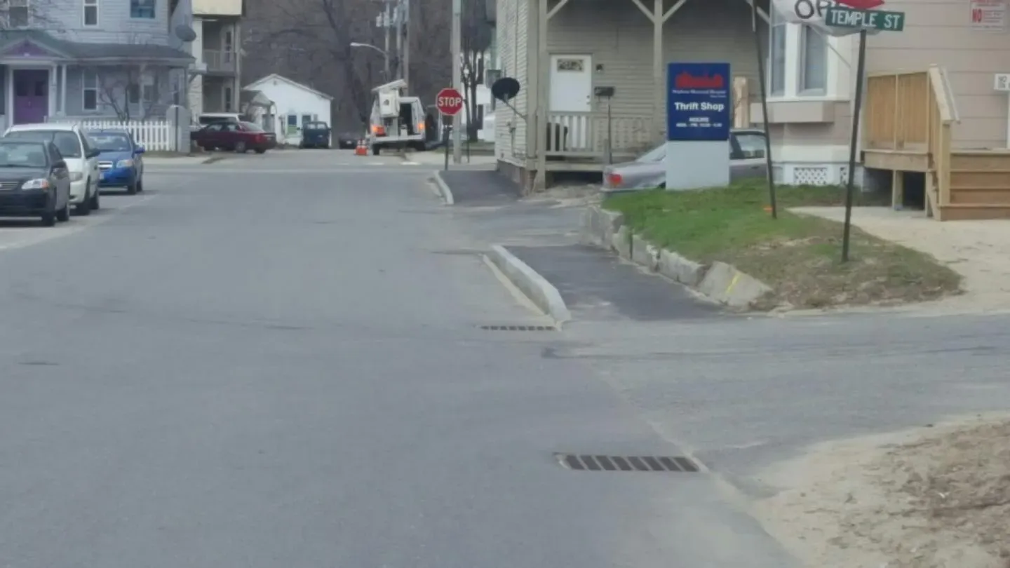 A street with cars parked on the side of it and a sign that says one way