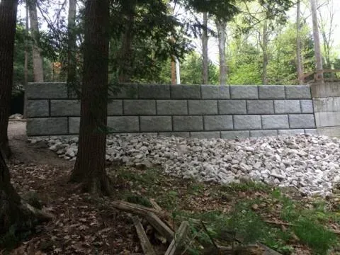 A large brick wall is surrounded by trees in the middle of a forest.